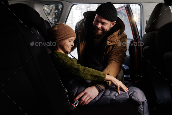 Dad fastening his daughter with seat belt before trip - Stock Photo - Images