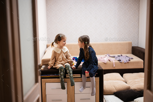 Two sisters sit on the sofa and tell and share girlish secrets with each other.