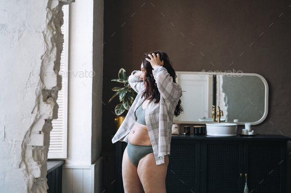 Self loving plus size middle aged woman in underwear in bathroom at home - Stock Photo - Images