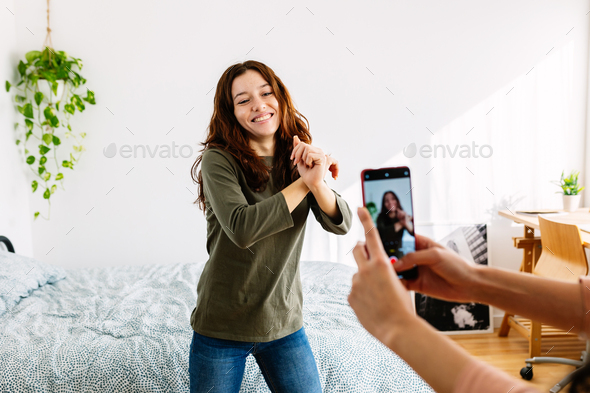Young female friends having fun recording video reels with phone
