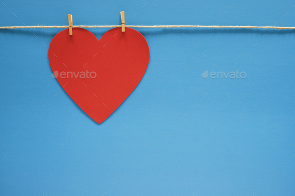 Red heart hanging on string with small clothes pins on blue background  Stock Photo by IrynaTolm