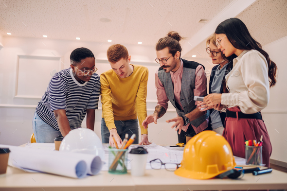Multiracial team of architects having a meeting while using blueprints - Stock Photo - Images