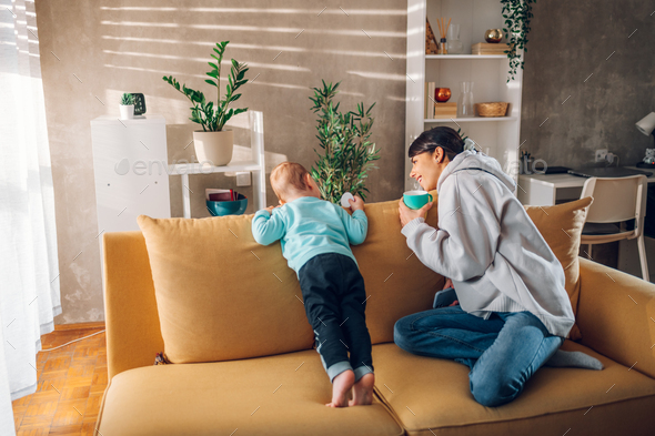 Mother playing and bonding with her child son and drinking coffee at home - Stock Photo - Images