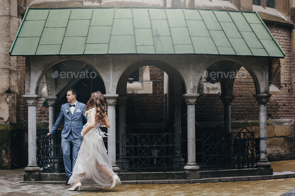 Stylish happy bride and groom walking on background of church . Provence wedding