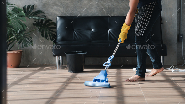 Person cleaning the room, the cleaning worker is using a mop to clean the floor of the living room.