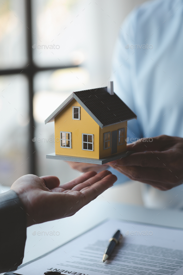 A housing salesman holds a model of a house and sends it to customers as an example.