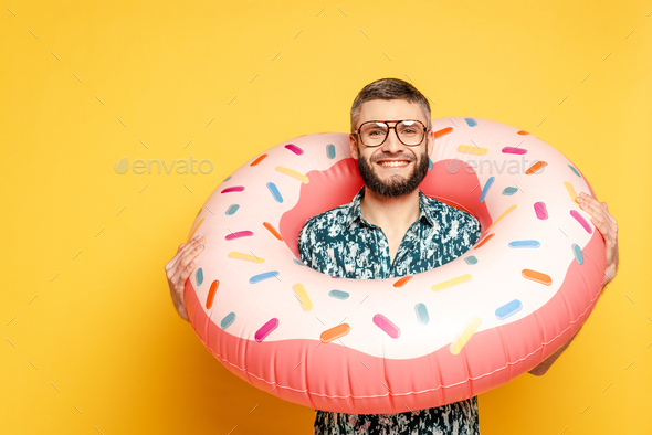smiling bearded guy in glasses with donut swim ring on yellow