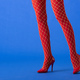 cropped view of woman in fishnet tights and red heels posing on blue Stock  Photo by LightFieldStudios