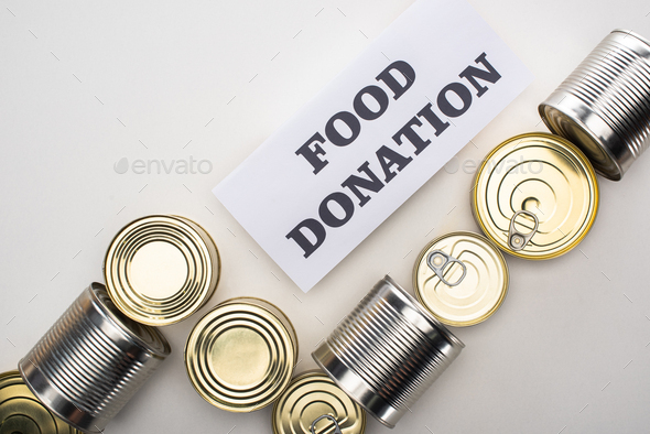 top view of cans with canned food on white background with food donation card