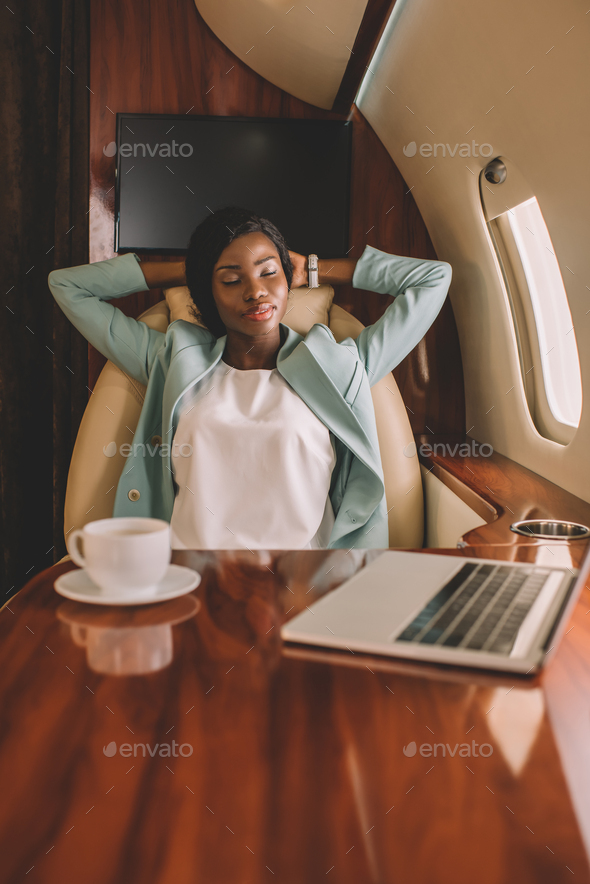 selective focus of african american businesswoman resting with closed eyes and hands behind head
