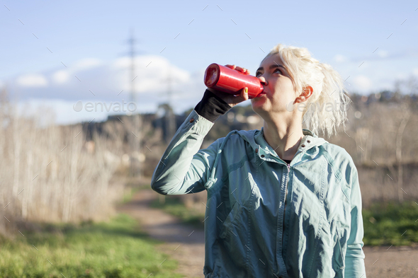 Young woman athlete takes a break, drinking water, out on a run on a hot day - Stock Photo - Images