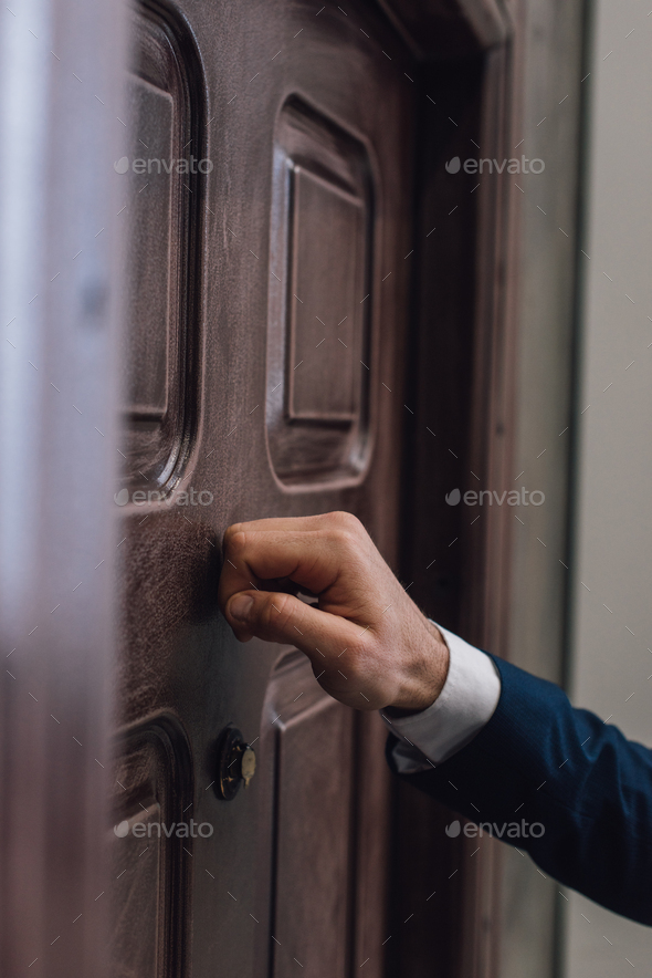 Partial view of collector knocking on door with hand