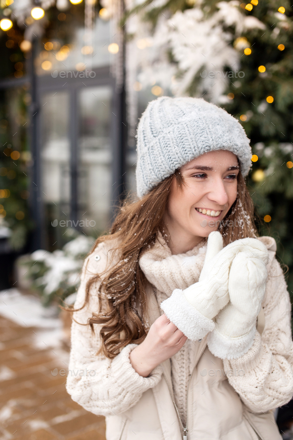 Smiling girl takes off her mittens to remove snow from her face