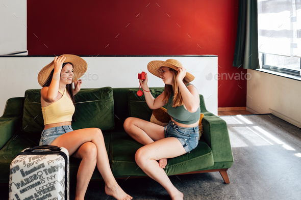 two young barefoot women wearing shorts just arrived in youth hostel tanking picture portrait