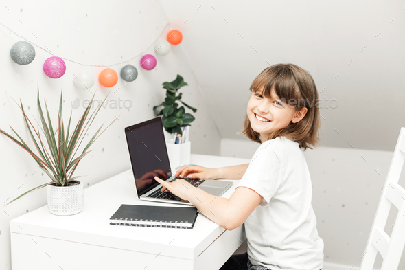Distance learning at home. A schoolgirl girl does her homework on a laptop or watches a webinar  - Stock Photo - Images