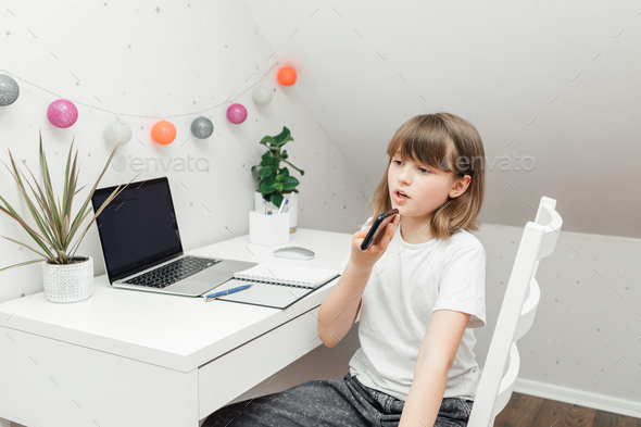 A teenage girl sits in her room and uses a mobile phone, writes or reads a message, makes a video - Stock Photo - Images