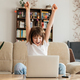 Online distance learning for children at home. The girl sits on the couch in front of a laptop  - PhotoDune Item for Sale