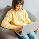 A girl sits in her room with a laptop on her lap and watches lessons or training courses. Children u - PhotoDune Item for Sale