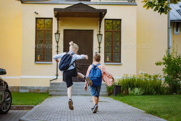 children running to school with backpacks on sunny day. Begining of academic year. - Stock Photo - Images