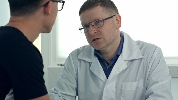 Male doctor in glasses consulting male patient
