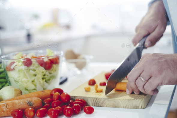 Chef at home using a knife cutting fresh raw vegetables. Cooker at home making a healthy meal