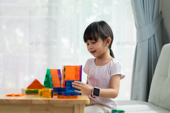A 5 years old asian little girl is pay attention to build the house toys from the magnetic blocks.