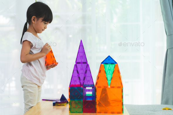 A 5 years old asian little girl is pay attention to build the house toys from the magnetic blocks.