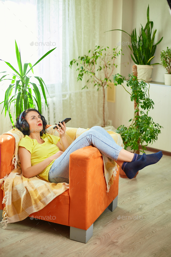 Woman in hedphones, lying on sofa, use virtual commands assistant on smartphone - Stock Photo - Images