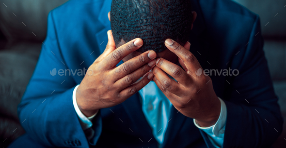 Black or African American business man sitting down looking anxious and depressed - Stock Photo - Images