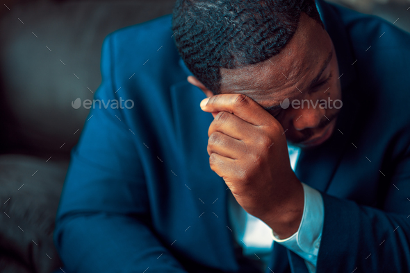 Black or African American business man sitting down looking anxious and depressed - Stock Photo - Images
