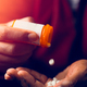 close up of man at home sitting down handling prescription pill bottle - PhotoDune Item for Sale