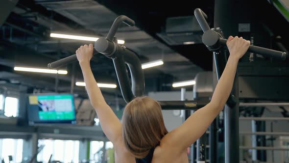 Woman Making Pulls Up Workout in Modern Gym