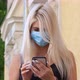 Young Blonde Woman in Protective Medical Mask Walks Down To the Street Uses Phone Texts Scrolls - VideoHive Item for Sale
