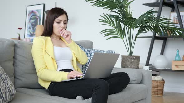 Sick Creative Woman Coughing while Sitting on Sofa and Typing on Laptop alt