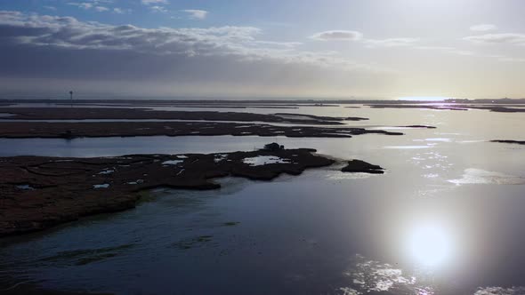 An aerial shot over Baldwin Bay near Freeport, NY during sunset. The camera dolly in high over the m alt