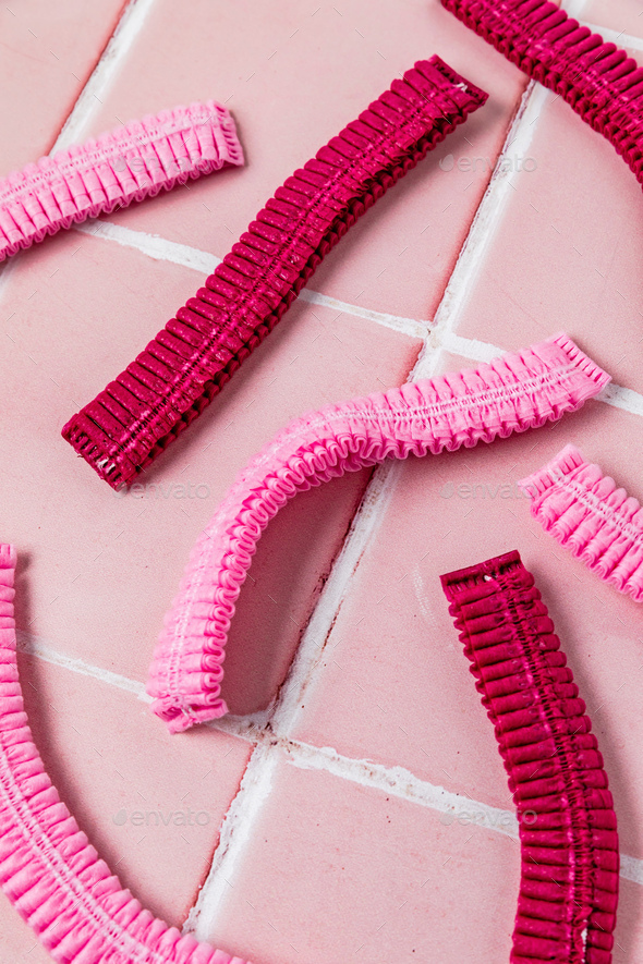 Disposable medical cap. Pink medical covering caps, top view. Surgical disposable caps on pink tile
