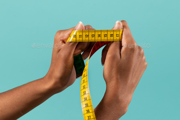 Black female hands showing measuring tape - Stock Photo - Images