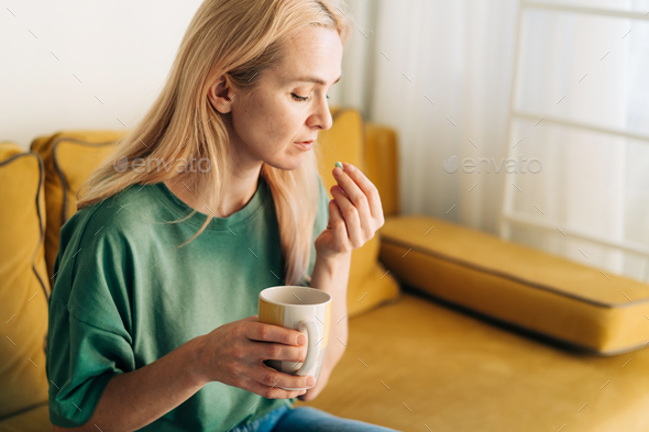 Sick unhappy woman holding a pill. Copy space - Stock Photo - Images