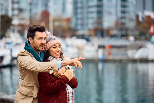 Embraced couple looking at something in the distance on a quay. - Stock Photo - Images