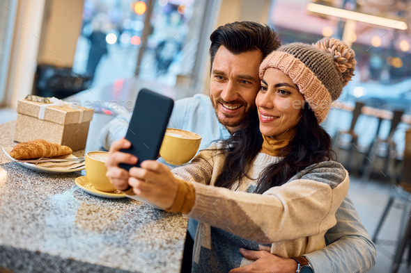 Happy couple taking selfie with smart phone in a cafe, - Stock Photo - Images