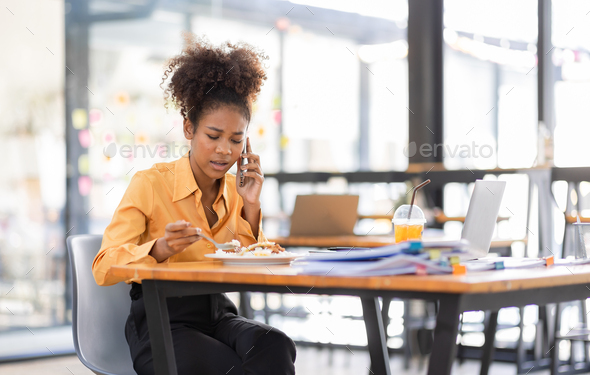Busy young business woman eating a Thai food lunch while working at workplace. A working woman