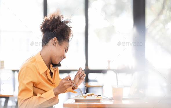 Busy young business woman eating a Thai food lunch while working at workplace. A working woman
