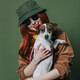 Stylish redhead woman with headphones and dog on green background - PhotoDune Item for Sale
