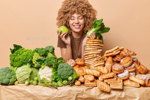 Happy woman prefers eating healthy fruits and vegetables instead of sweet desserts keeps eyes closed - Stock Photo - Images