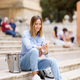 Glad woman with smartphone sitting on steps - PhotoDune Item for Sale