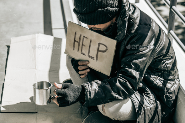 Beggar,Homeless adult man sitting on the street to get help. Indifference of people. Social issues.