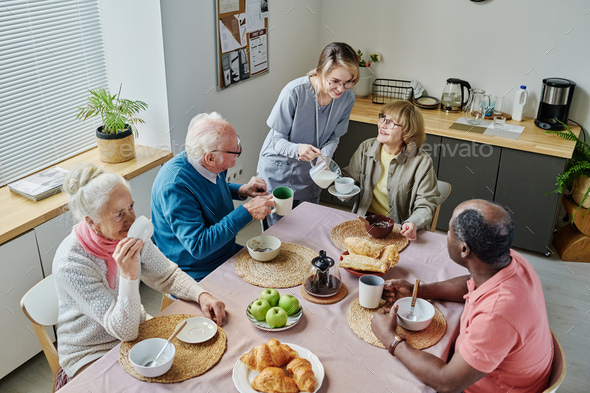 Caregiver caring about senior people during lunch - Stock Photo - Images