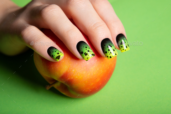 Female neat hand with short natural nails painted with green nail polish holding apple.  - Stock Photo - Images