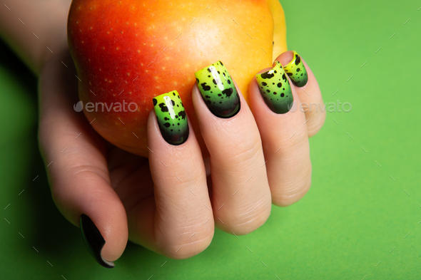 Female neat hand with short natural nails painted with green nail polish holding apple.  - Stock Photo - Images