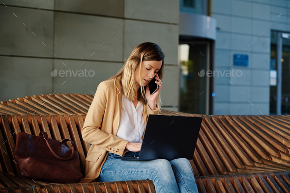Woman sitting with a laptop on steps outdoors against sunset. - Stock Photo - Images